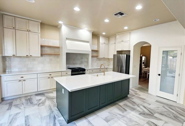 A kitchen with white cabinets and a large island in the middle.