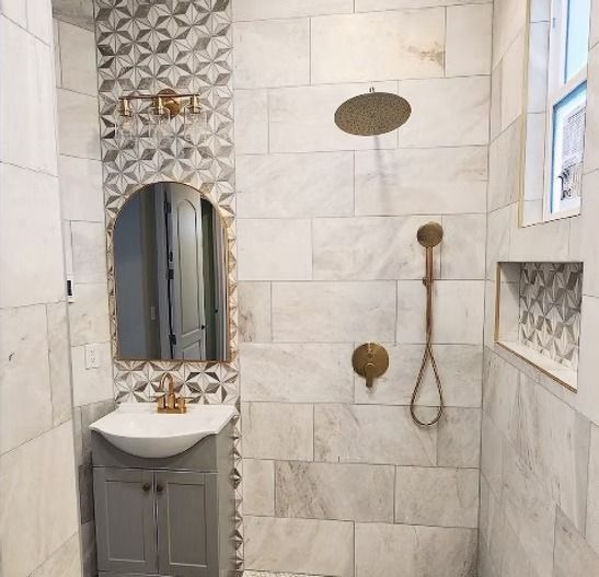 A bathroom with a sink , shower and mirror.