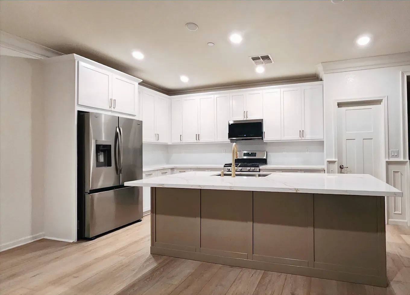A kitchen with white cabinets , stainless steel appliances , and a large island.