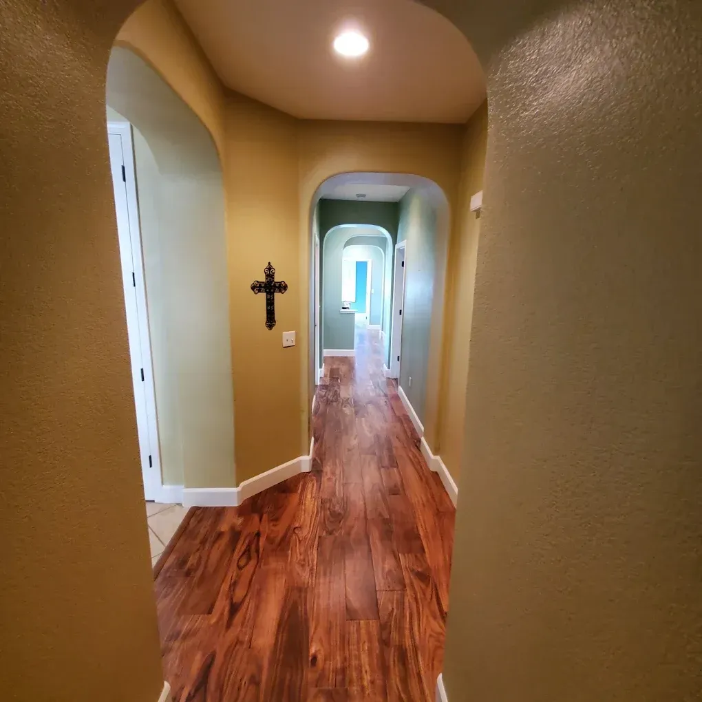A hallway with hardwood floors and a cross on the wall