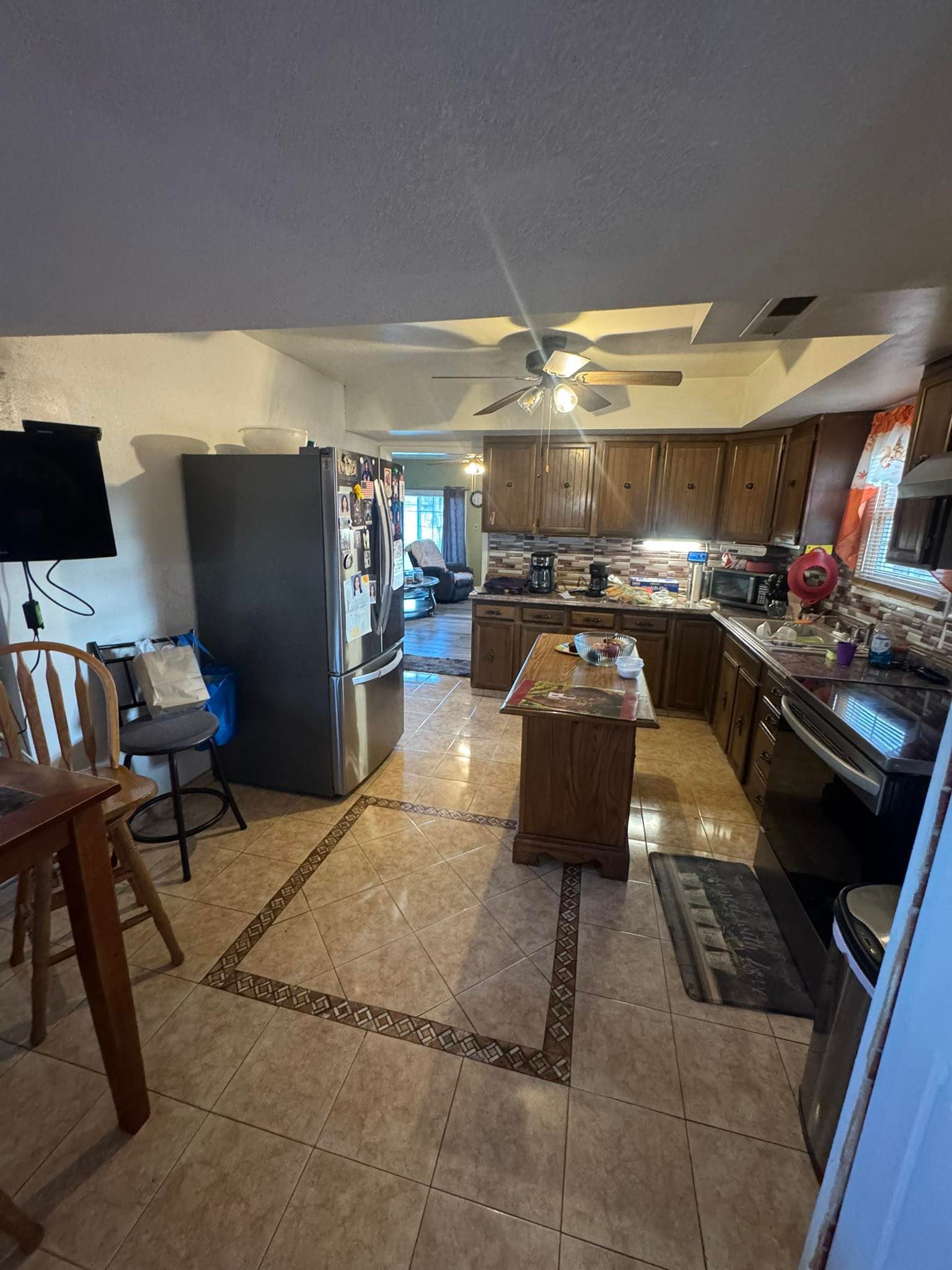 A kitchen with a table , chairs , refrigerator and microwave.