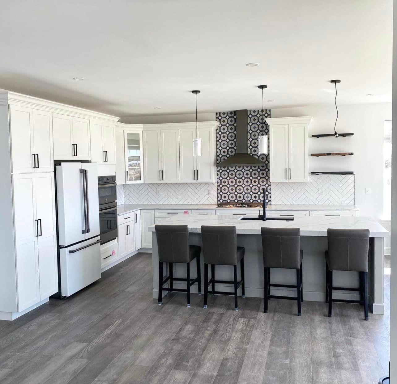 A kitchen with white cabinets , a refrigerator , a sink , and a large island.