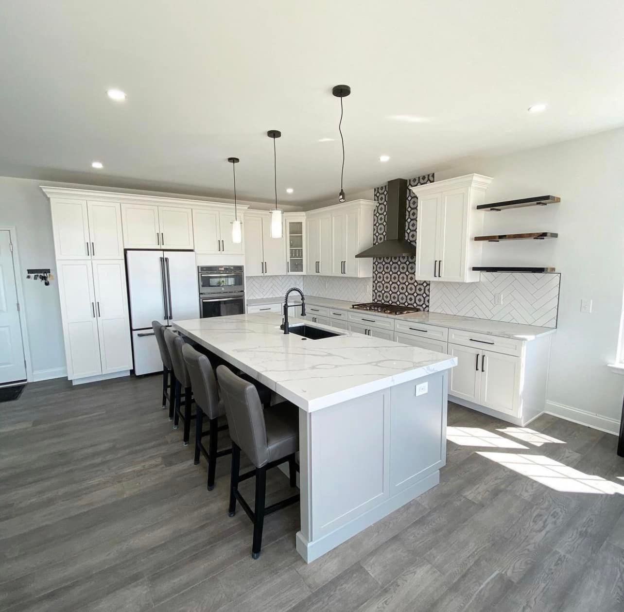 A kitchen with white cabinets and a large island in the middle.