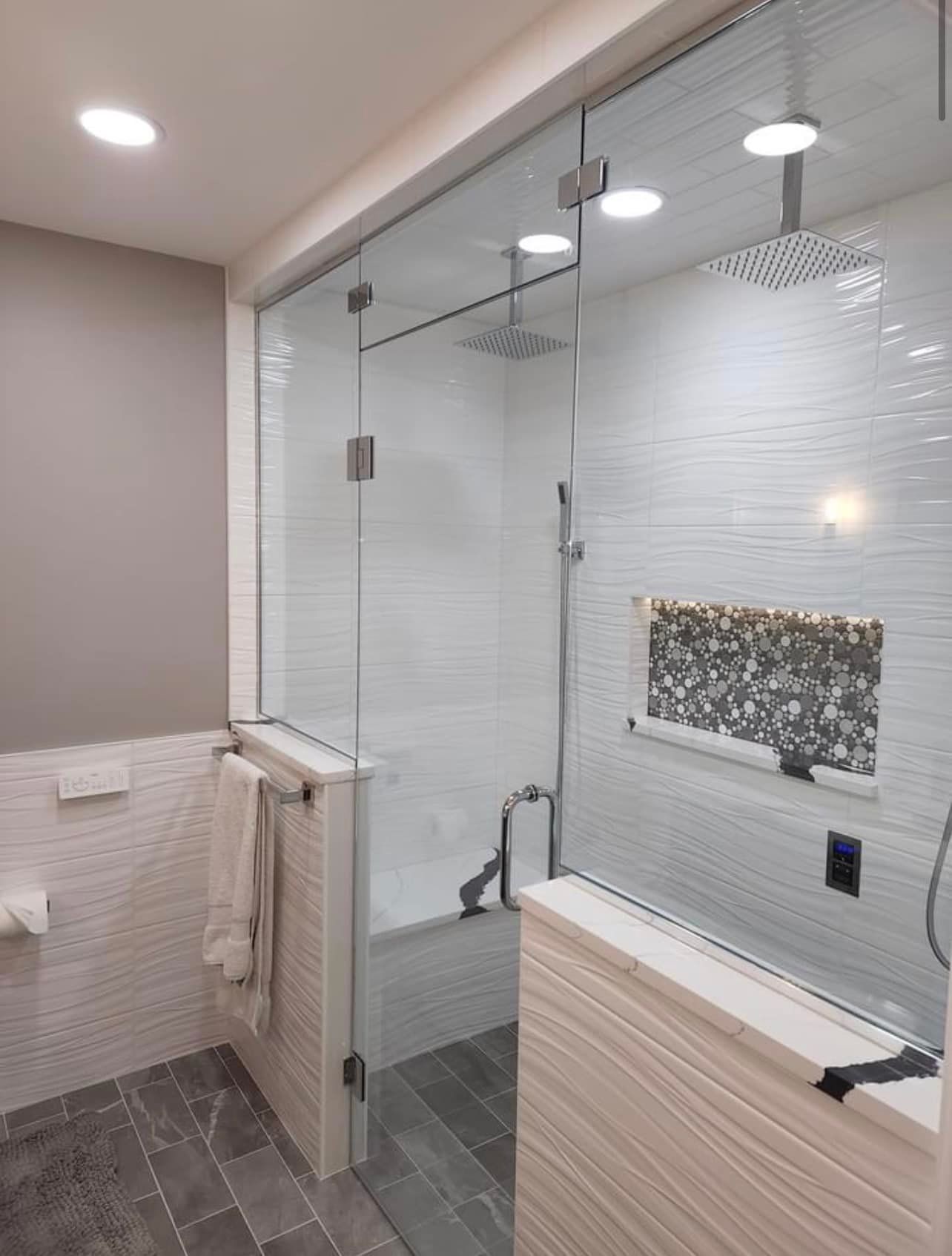 A bathroom with a walk in shower with a glass door.