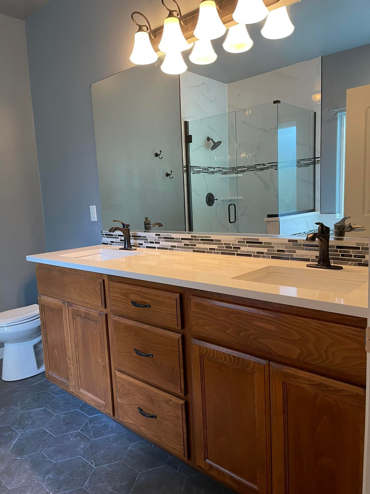 A bathroom with two sinks , a toilet , and a large mirror.