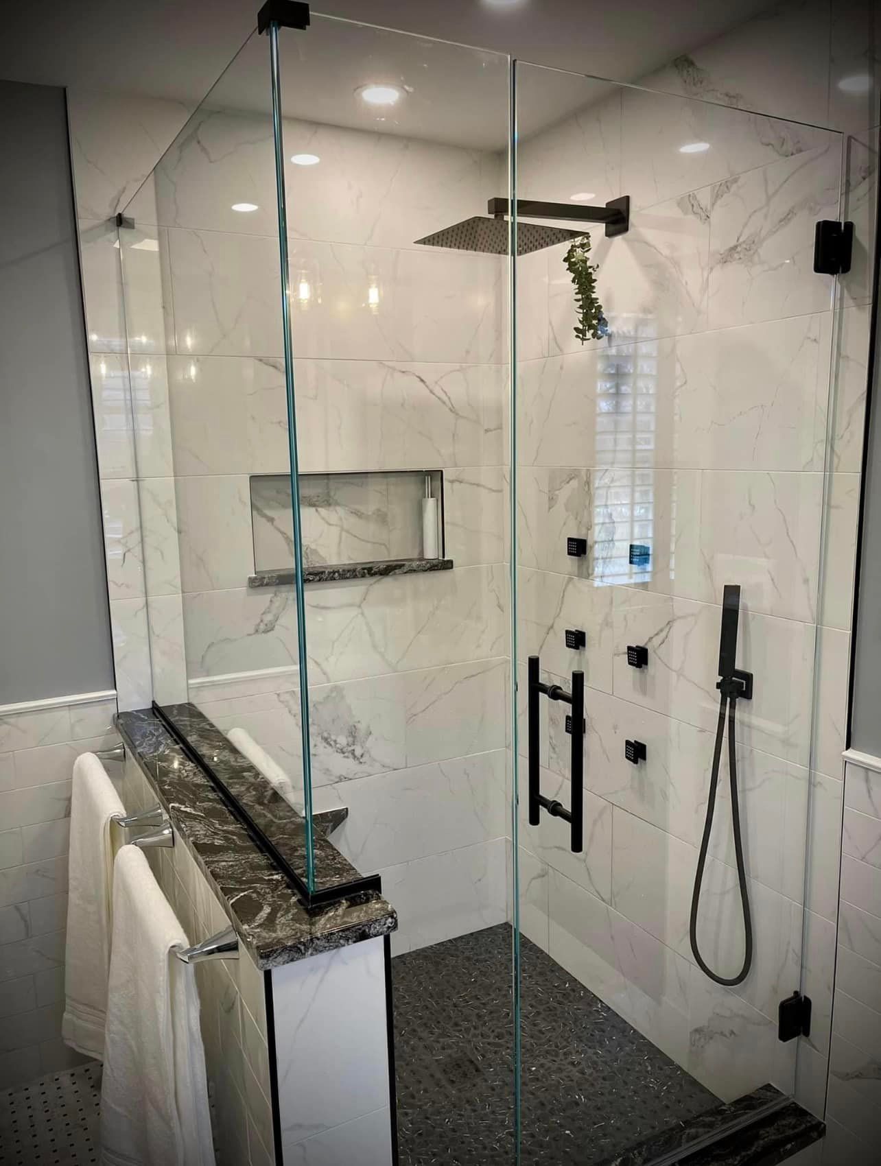 A bathroom with a walk in shower with a glass door and a shower head.