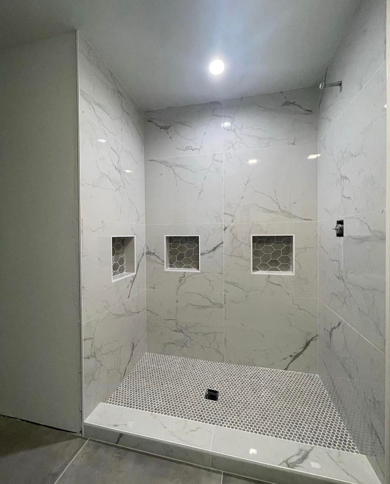 A bathroom with a walk in shower and marble walls.