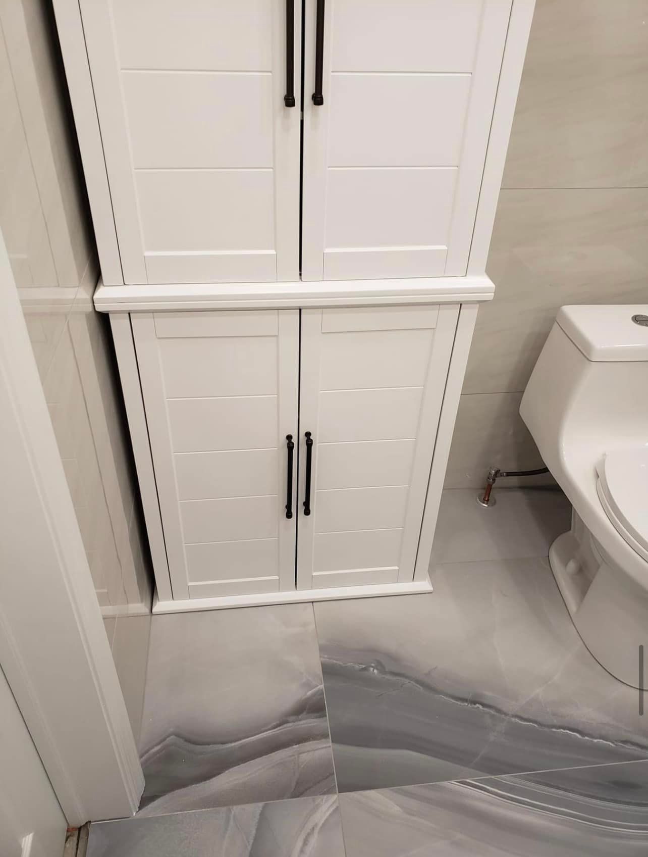 A bathroom with a toilet and a white cabinet.