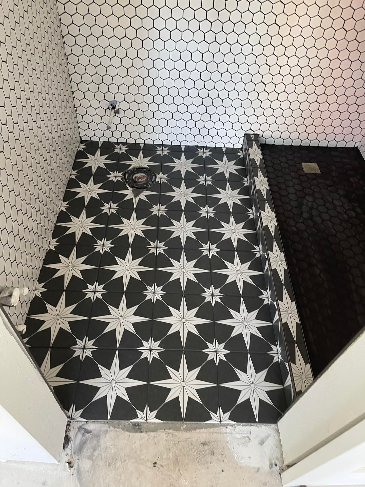 A bathroom with a black and white tile floor with stars on it.