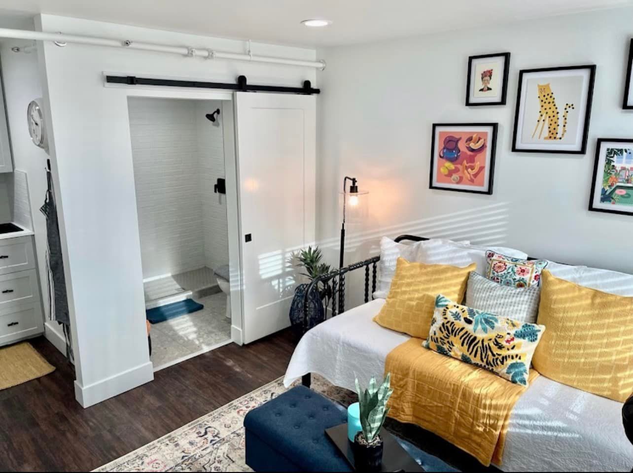 A bedroom with a couch , bed , and sliding barn doors leading to a bathroom.