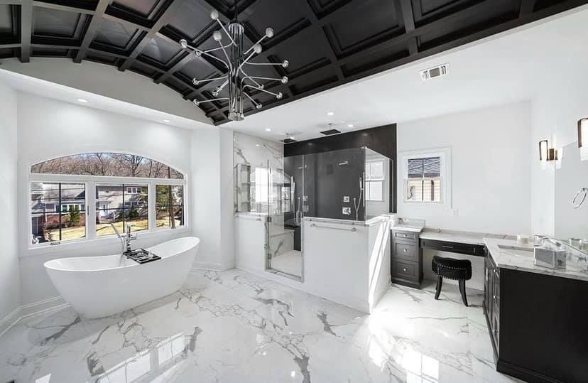 A bathroom with a bathtub , sink , mirror and marble floor.