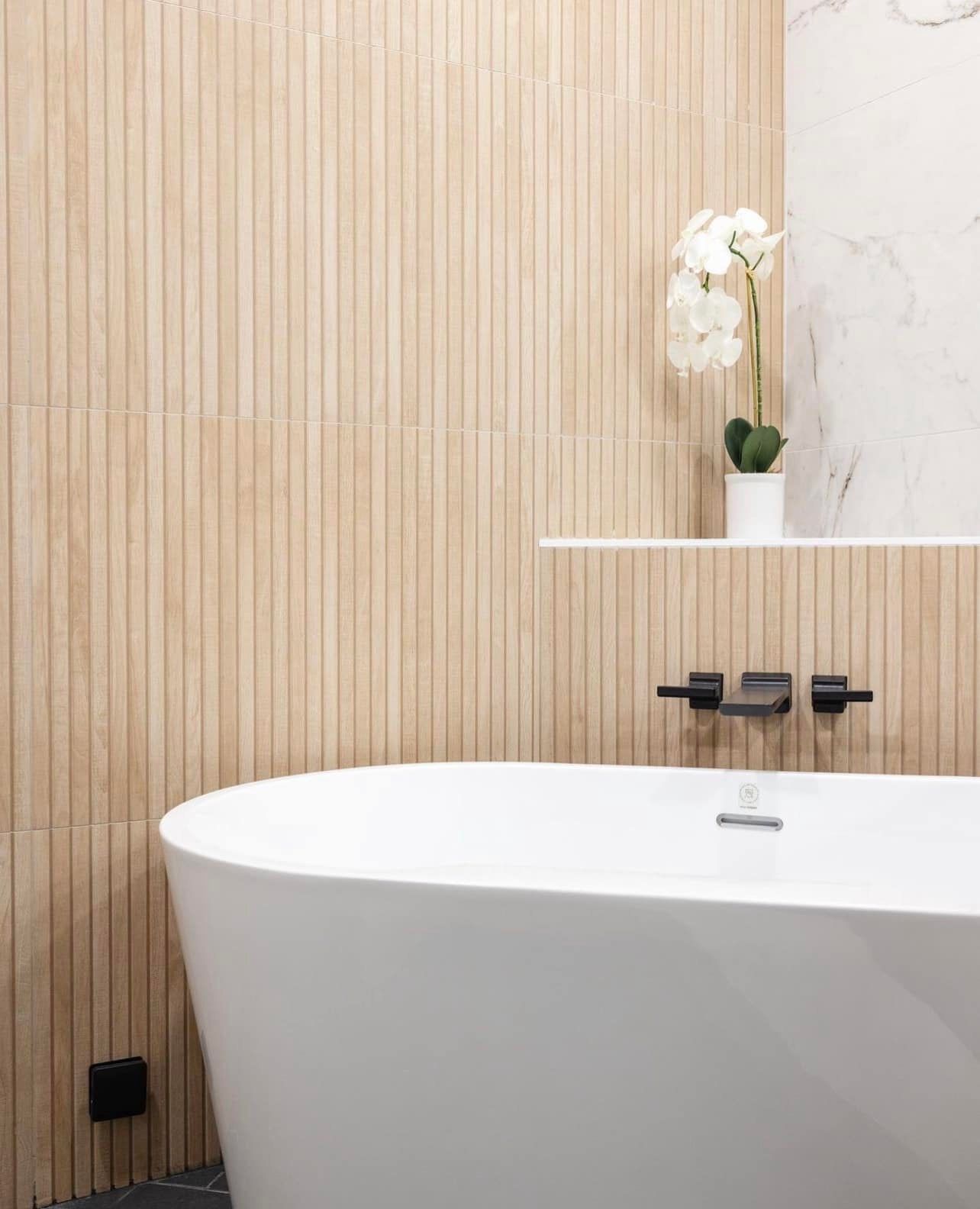 There is a bathtub in the bathroom with wooden walls.