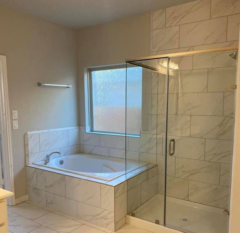 A bathroom with a tub and a shower with a glass door.