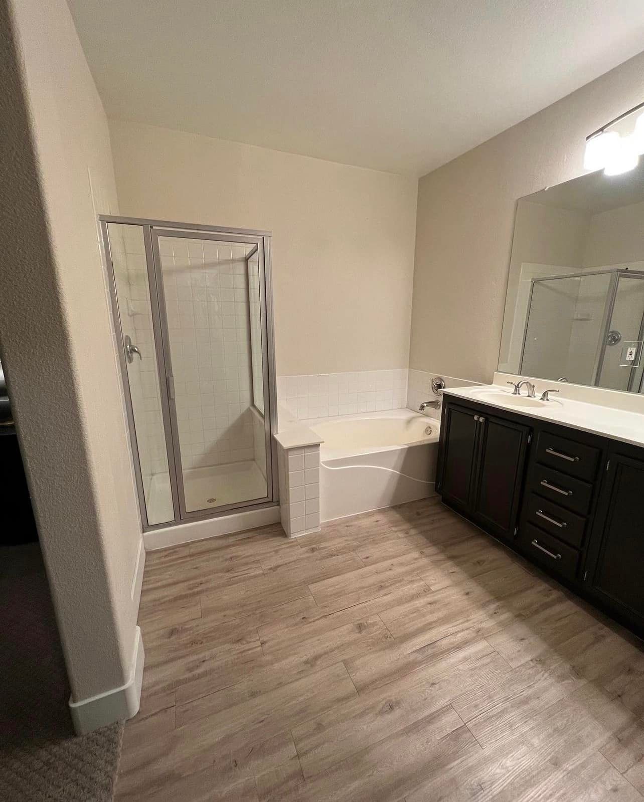 A bathroom with a tub , sink , shower and mirror.