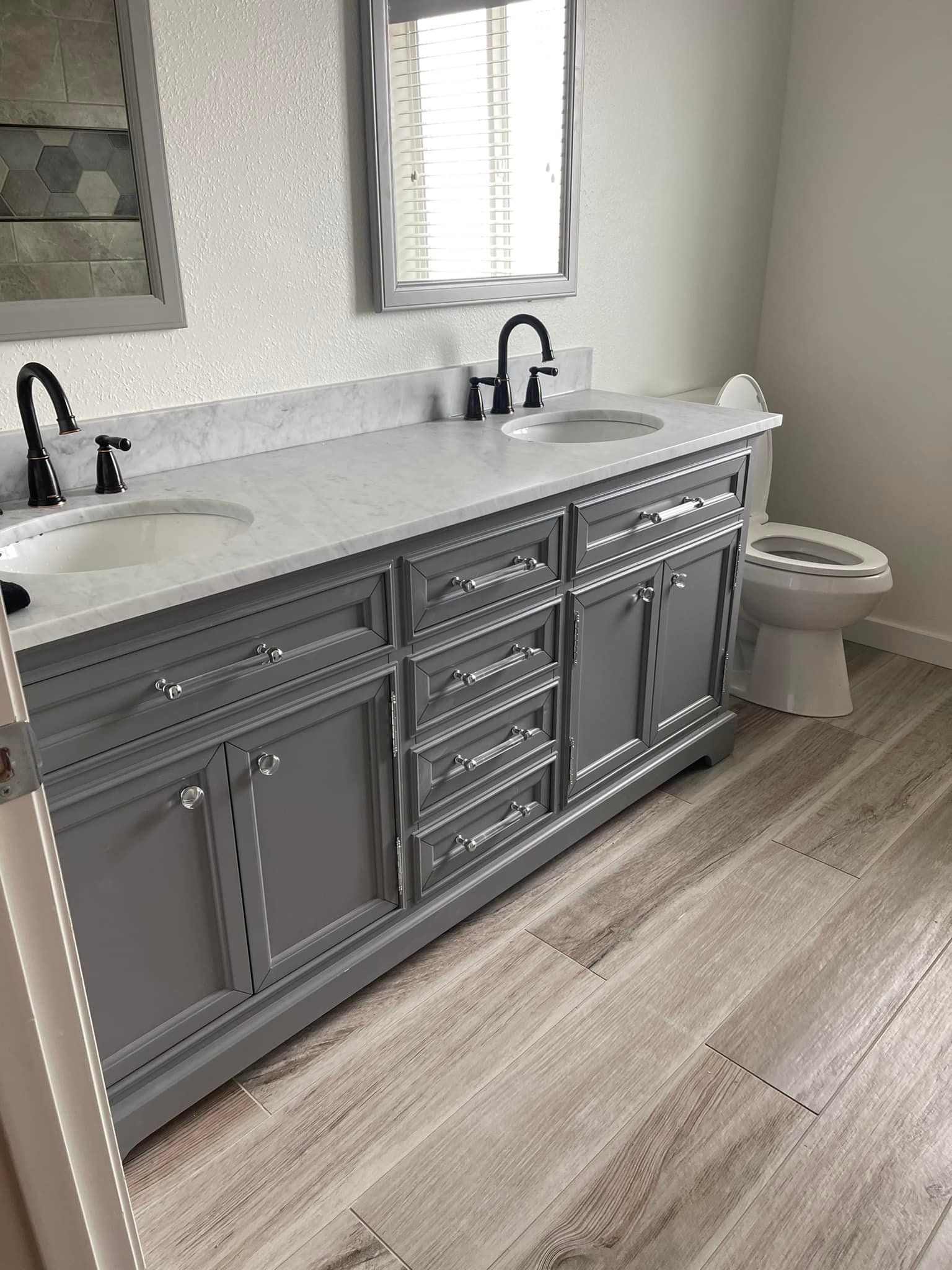 A bathroom with two sinks , a toilet and a mirror.