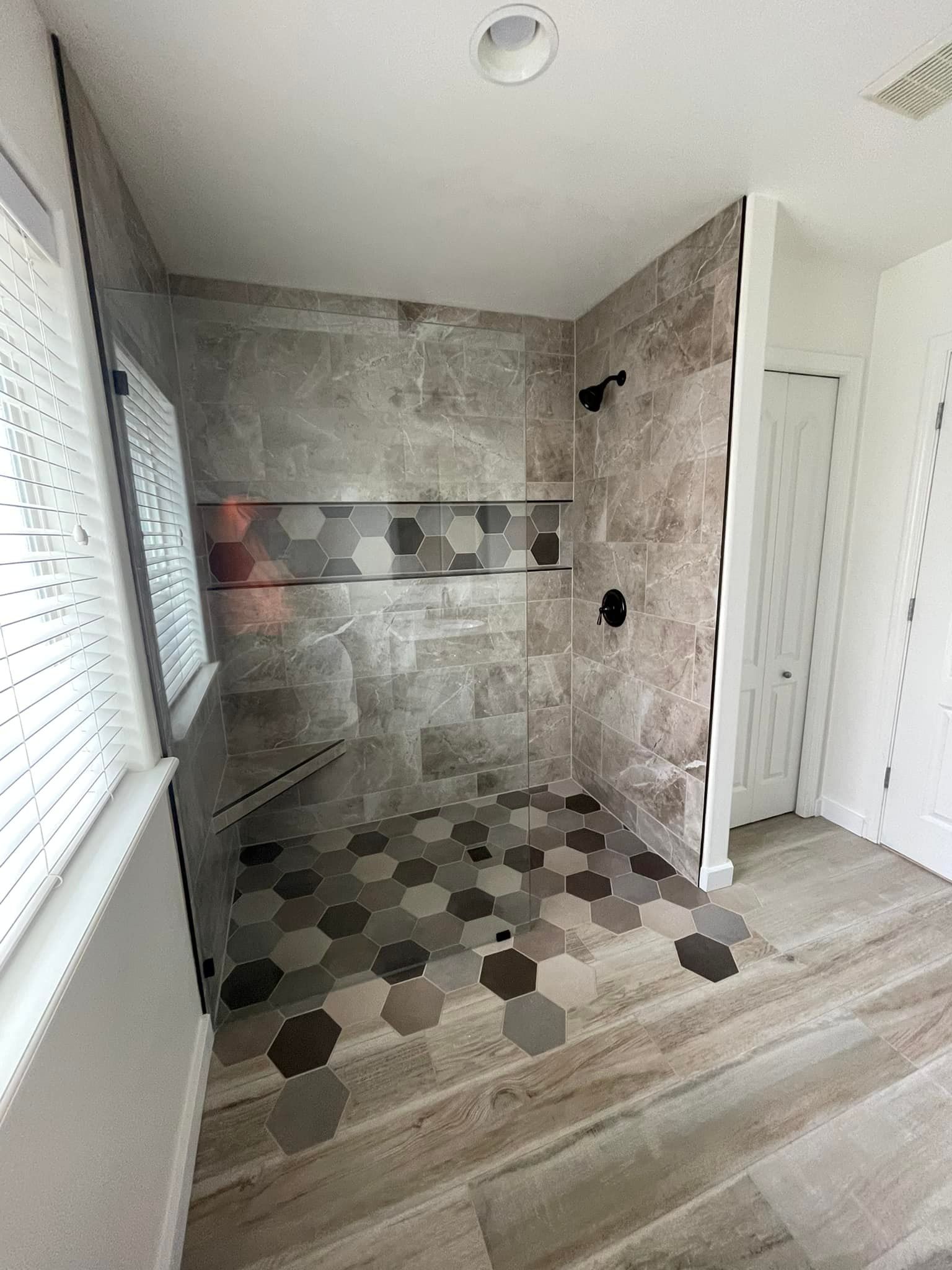 A bathroom with a walk in shower and a window.