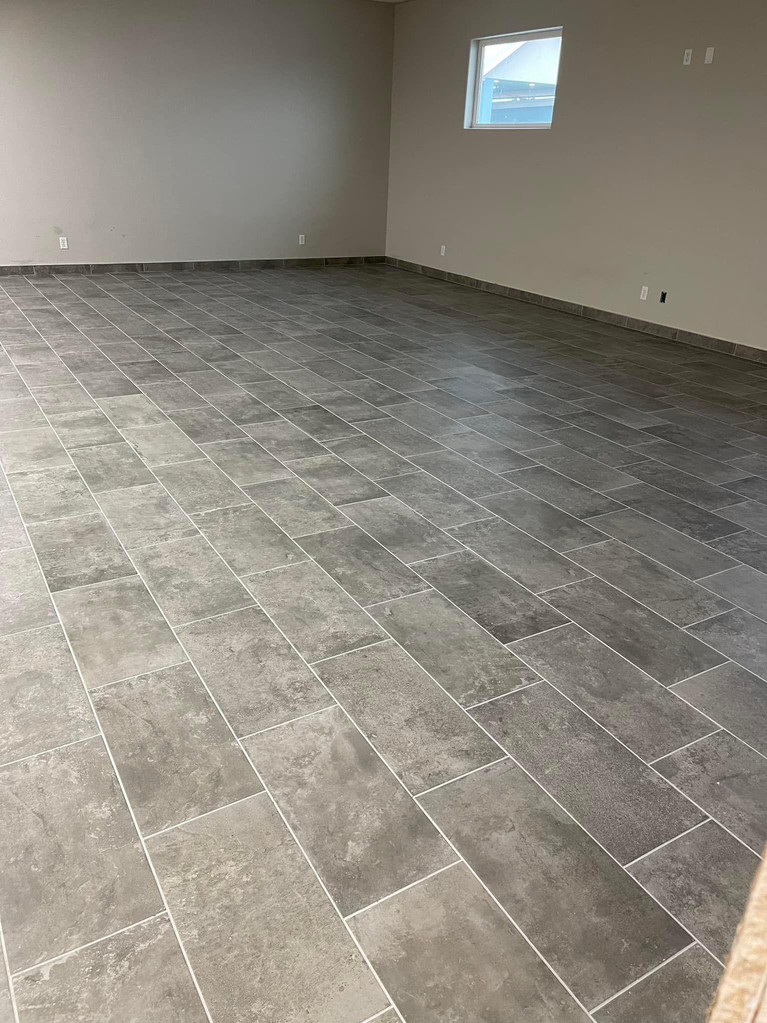 A large room with a tiled floor and a window.