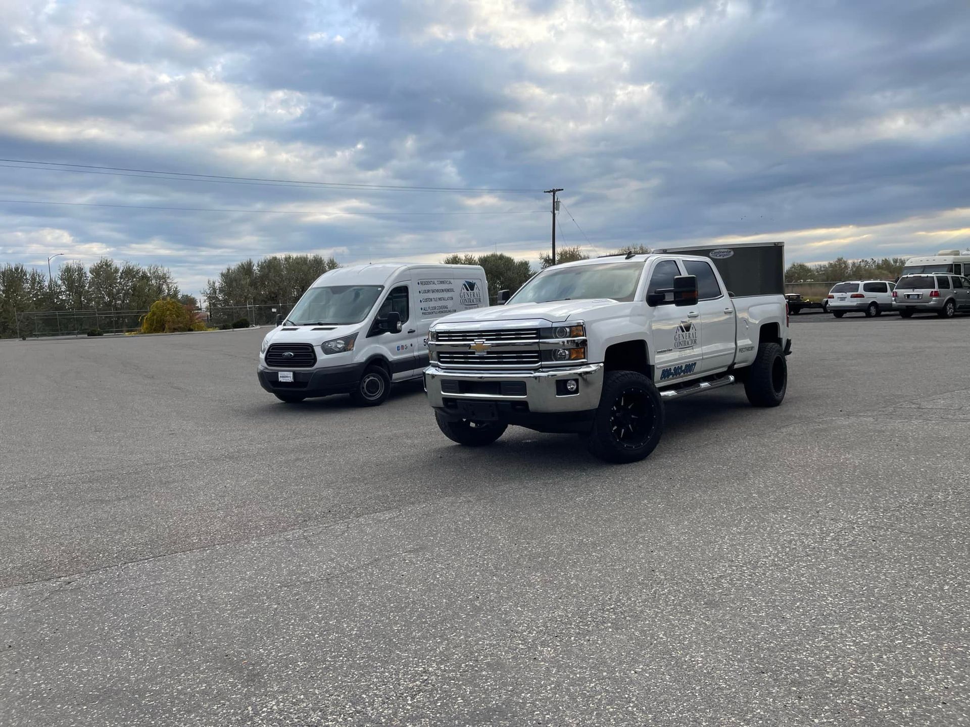 Two white trucks are parked next to each other in a parking lot.