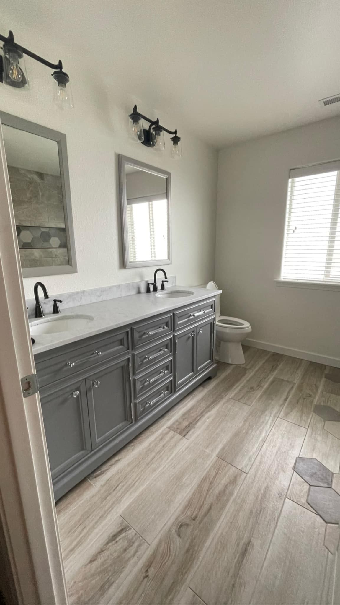 A bathroom with two sinks , a toilet , and a mirror.