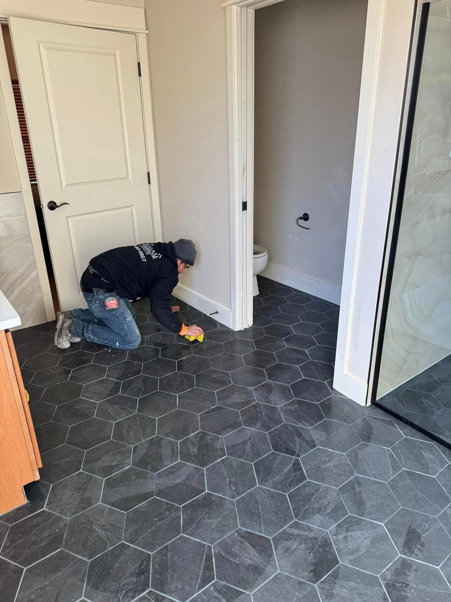 A man is kneeling on the floor in a bathroom.