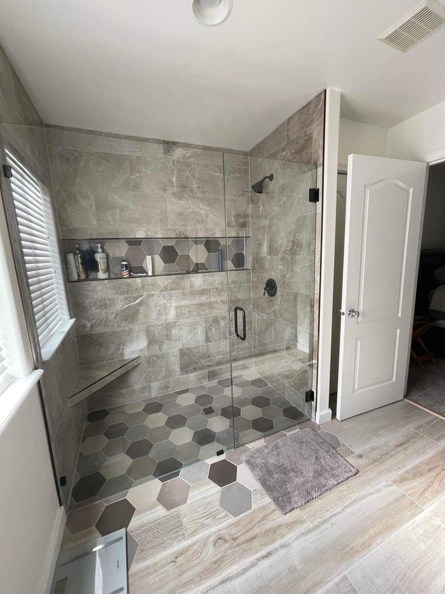 A bathroom with a walk in shower with a glass door.