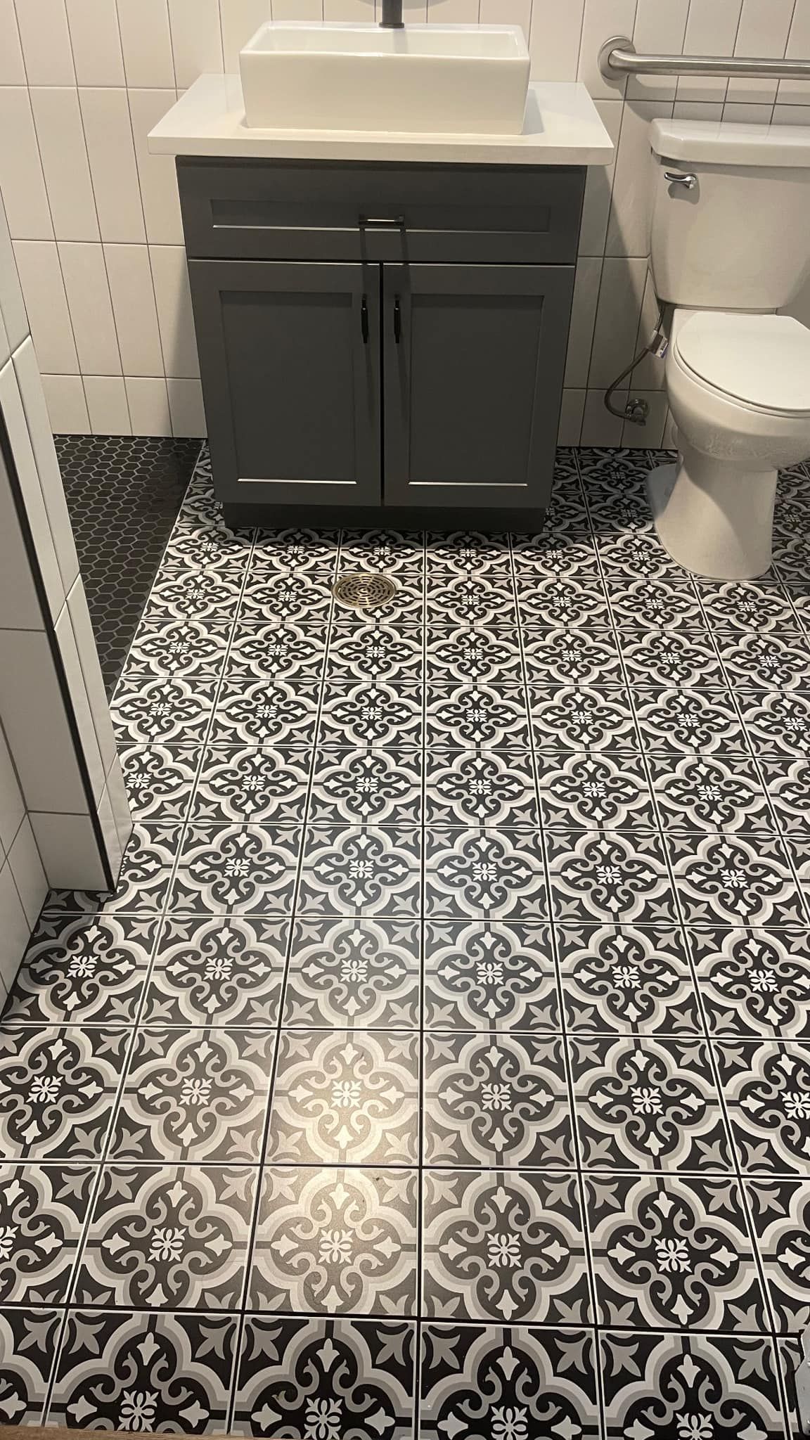 A bathroom with a sink , toilet , and black and white tile floor.