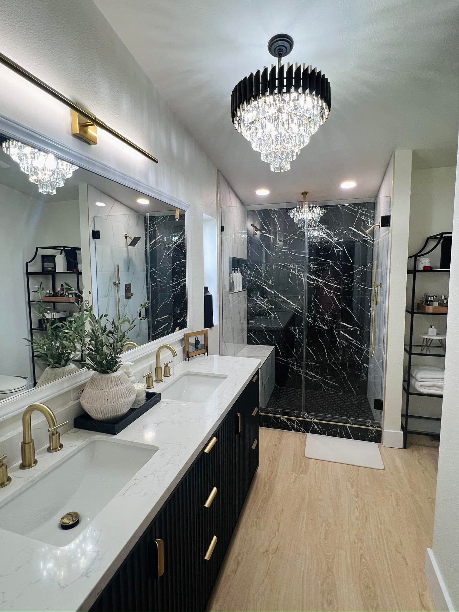 A bathroom with two sinks , a shower and a chandelier.