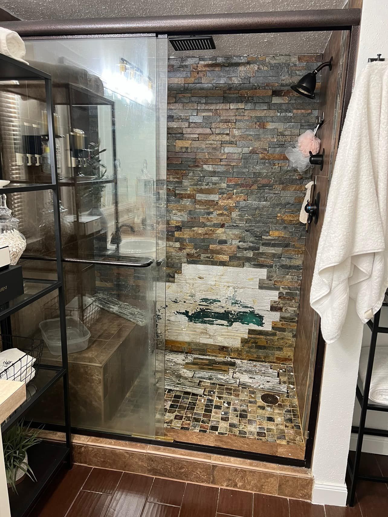 A bathroom with a sliding glass shower door and a brick wall.