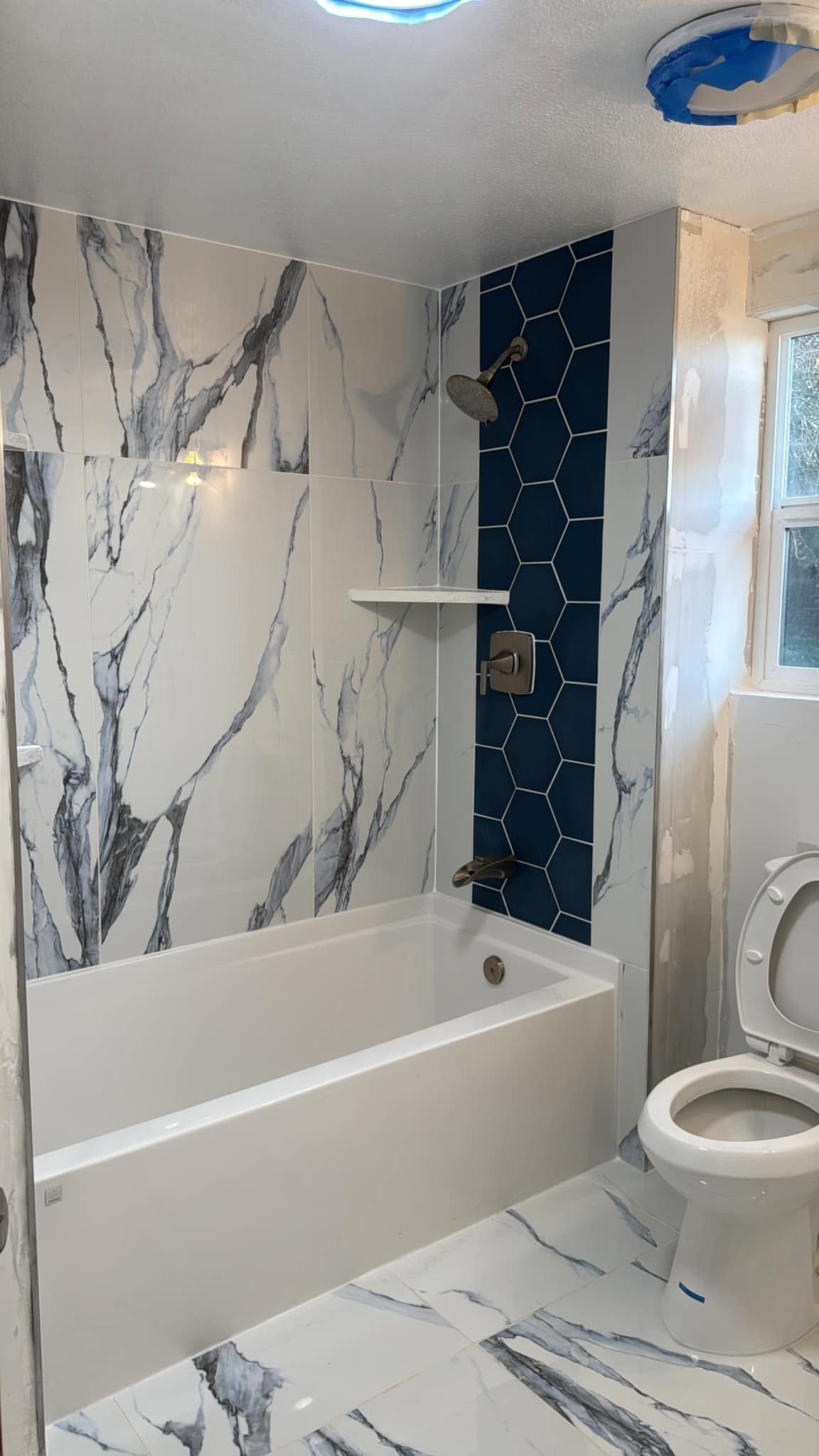 A bathroom with a bathtub , toilet and shower.