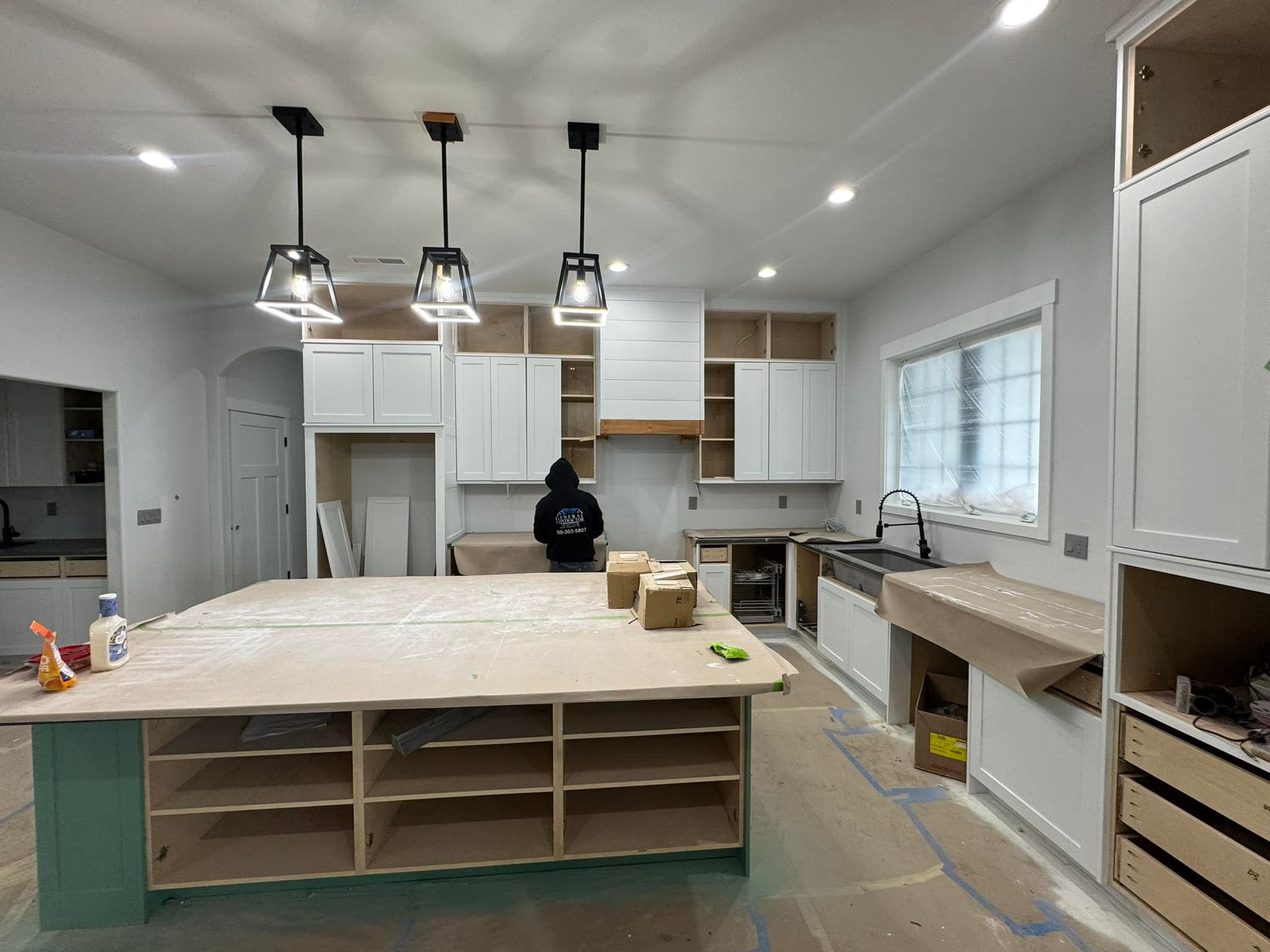 A kitchen under construction with a large island in the middle.