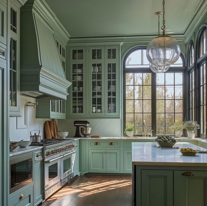 A kitchen with green cabinets and a large window