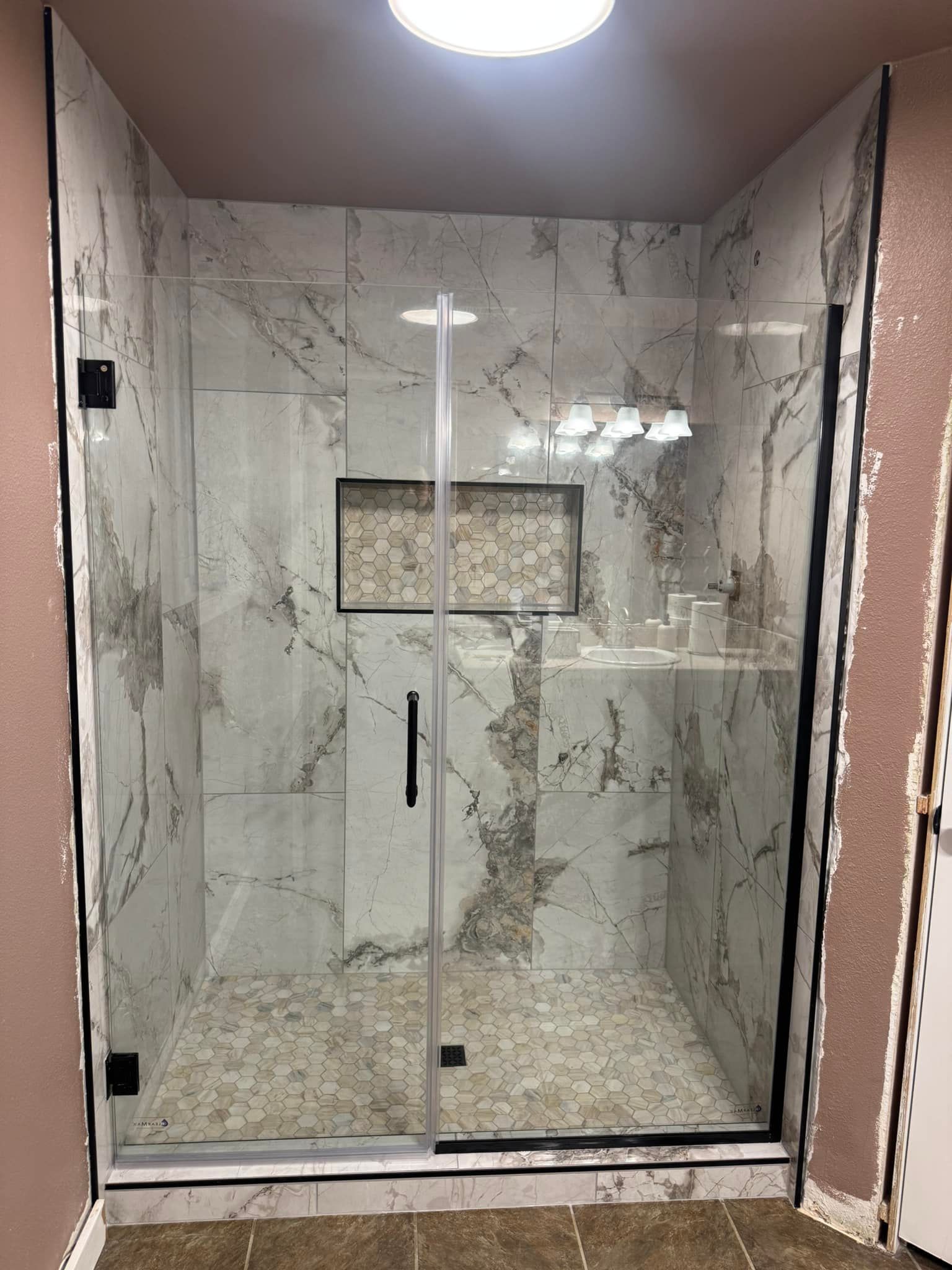 A bathroom with a walk in shower with a glass door.