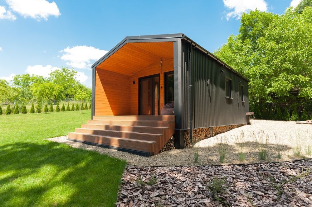 A small house with stairs leading up to it is sitting on top of a lush green field.