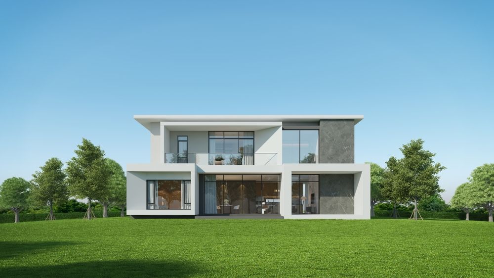 A modern house with a lot of windows is sitting on top of a lush green field.