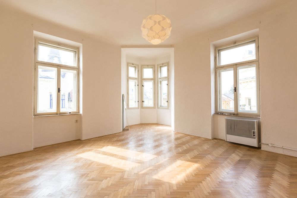 An empty living room with hardwood floors and lots of windows.