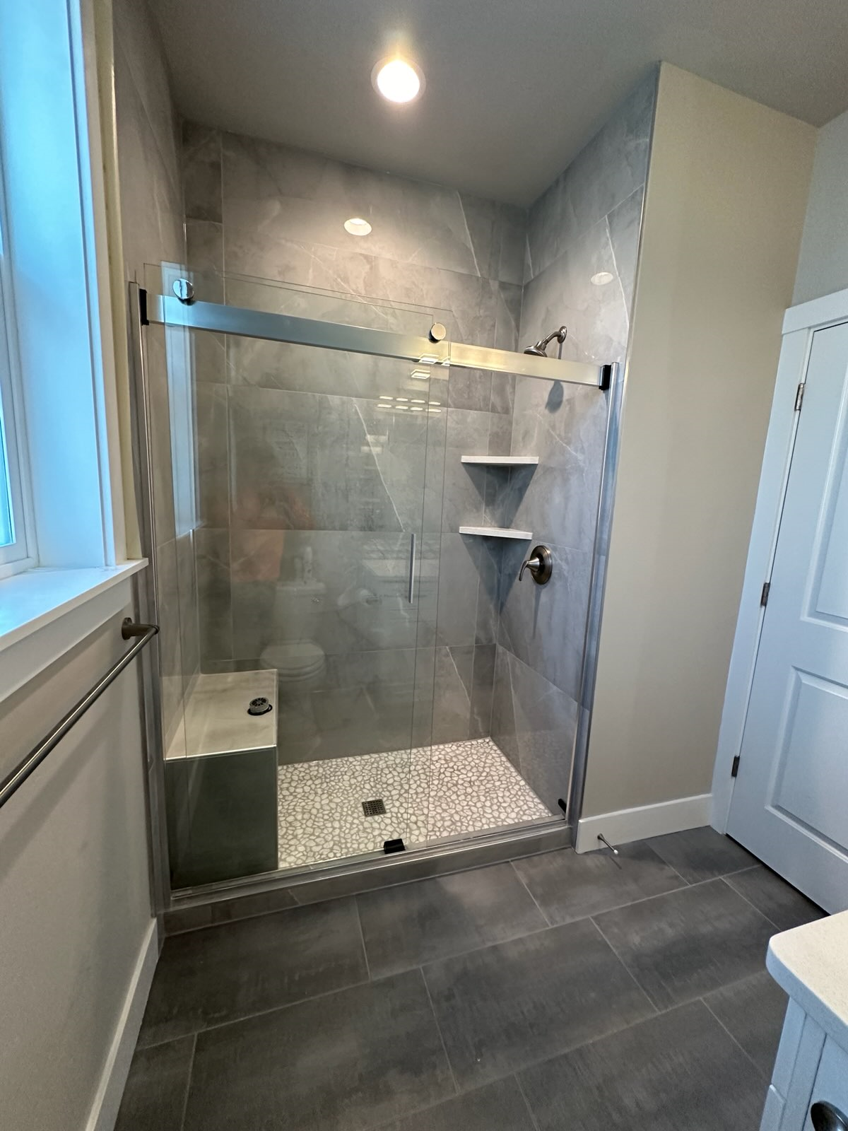 A bathroom with a walk in shower and a window.