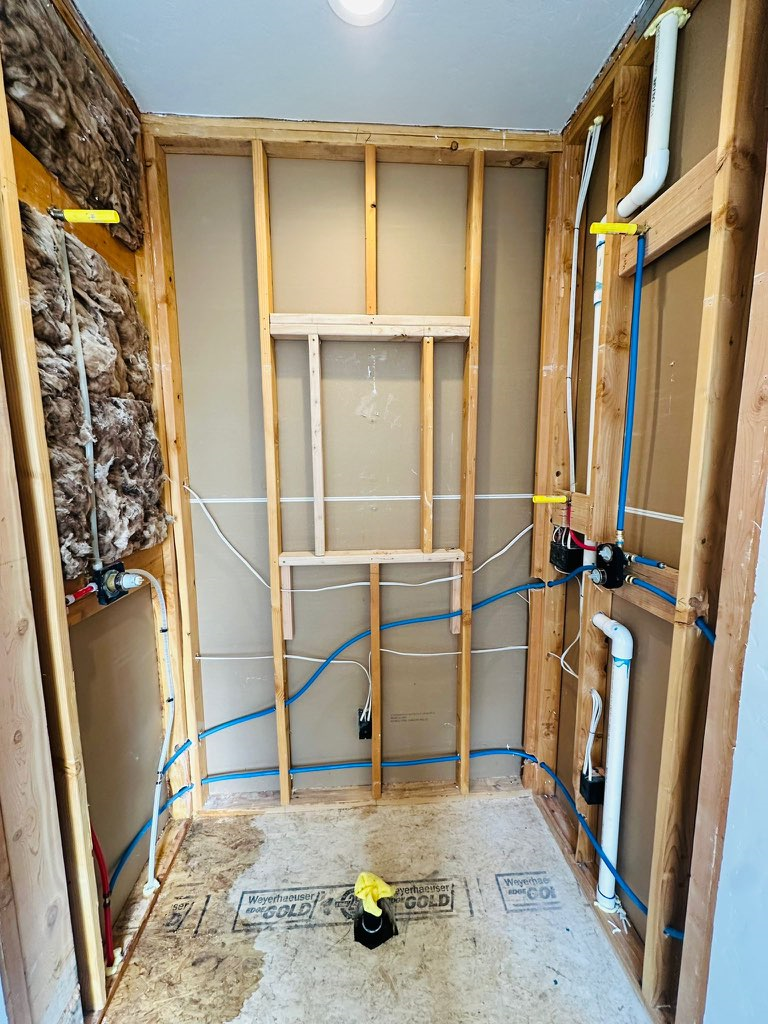 A bathroom under construction with wooden walls and pipes.