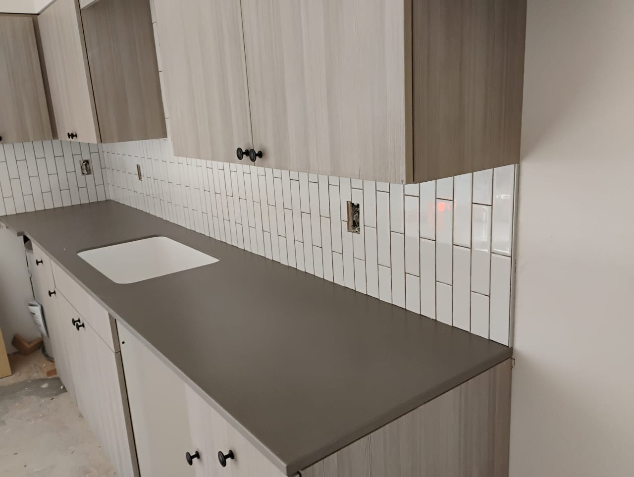 A kitchen with a sink and a gray counter top