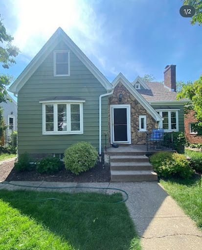 A small house with a green siding and white windows