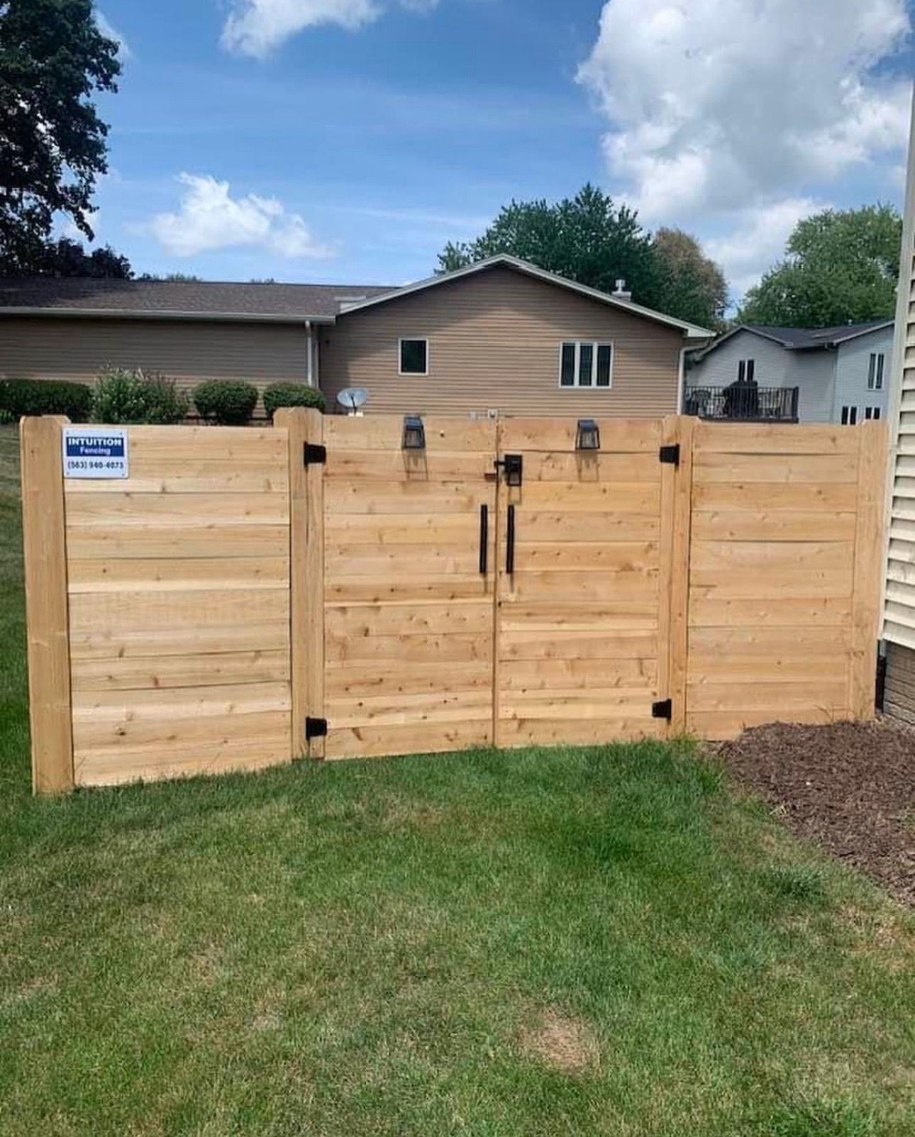 A wooden fence with a gate in front of a house.