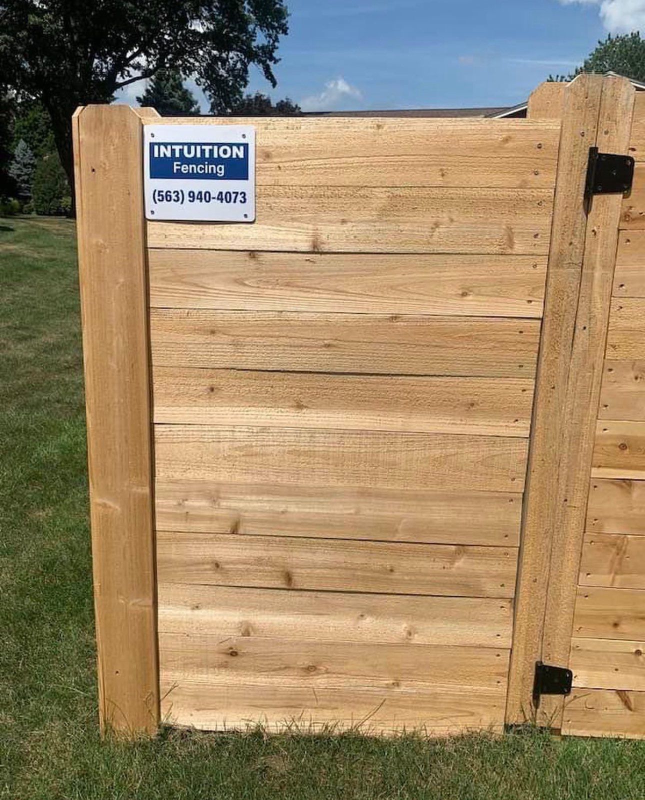 A wooden fence is sitting on top of a lush green field.
