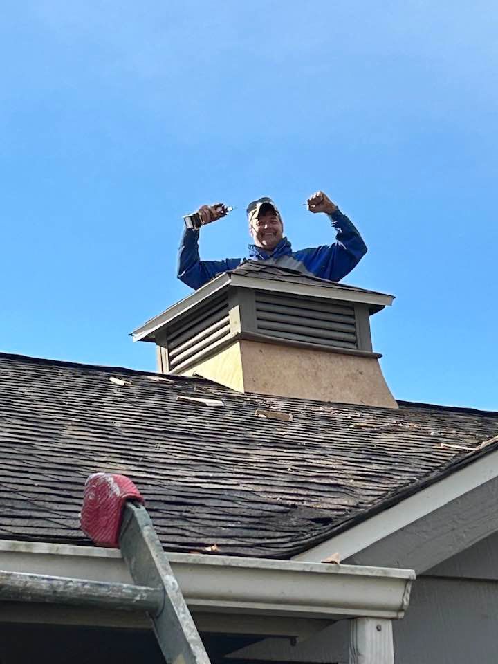A man is standing on top of a chimney on a roof.