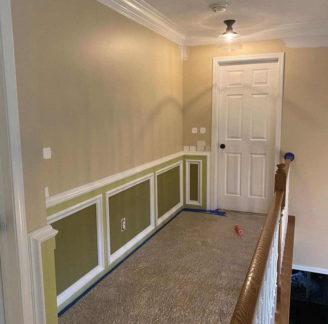 A hallway with a staircase and a door is being painted.