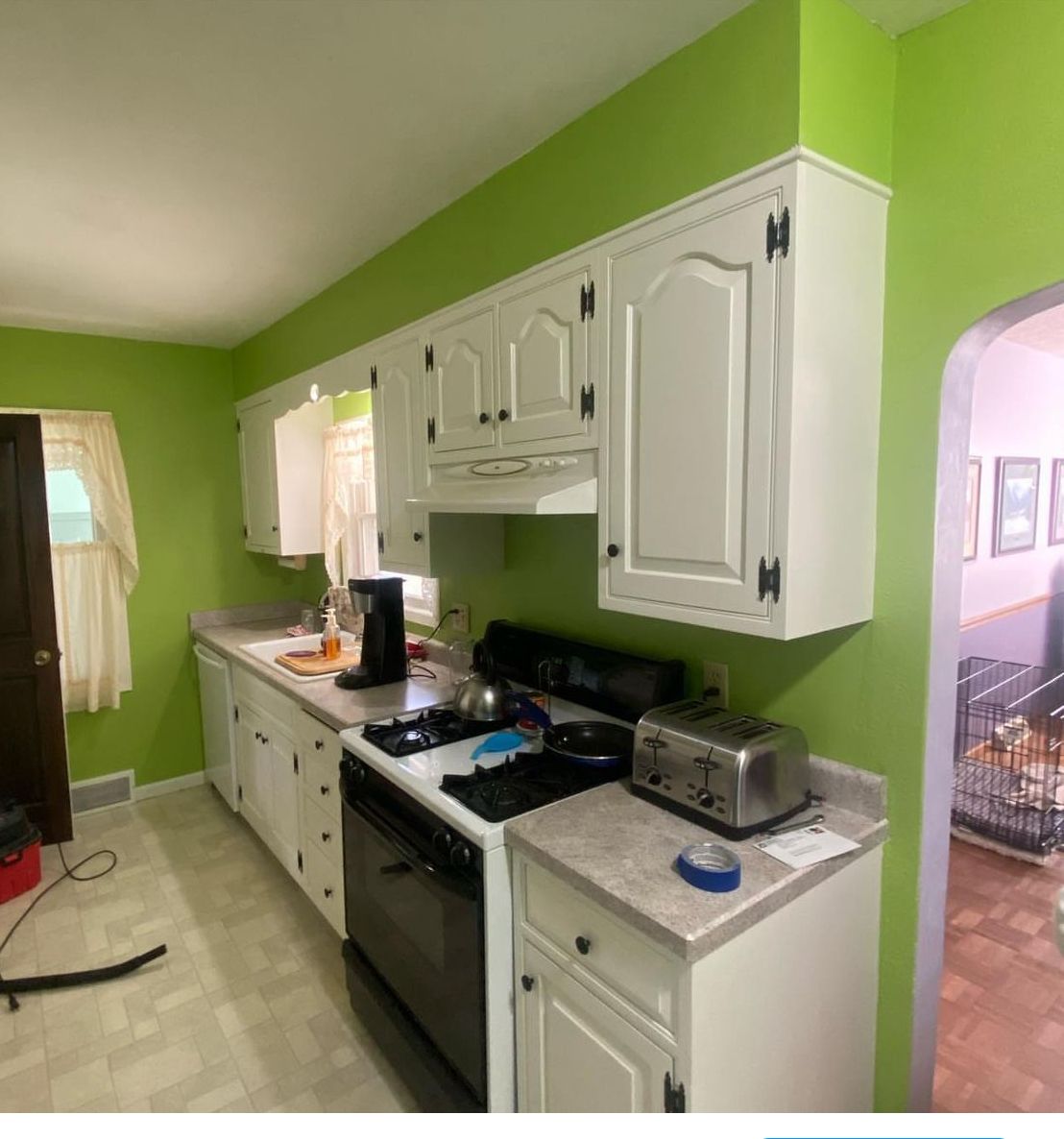 A kitchen with green walls and white cabinets