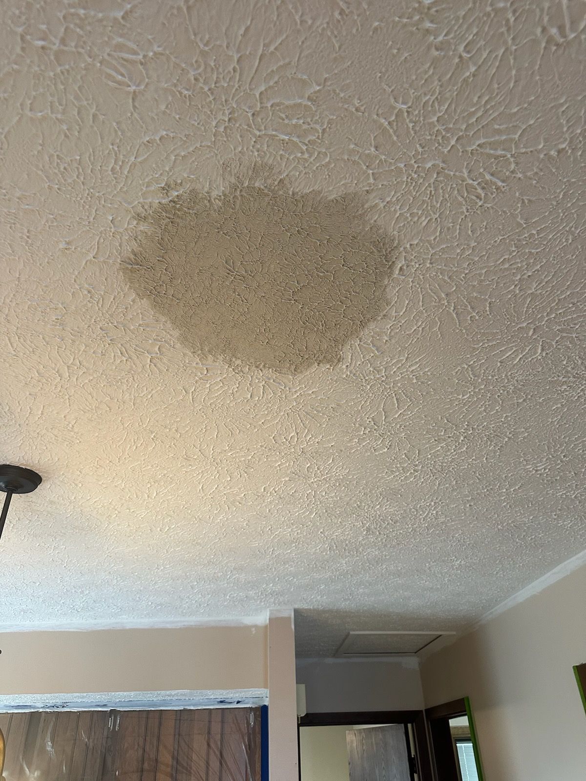 A ceiling with a hole in it and water coming out of it.