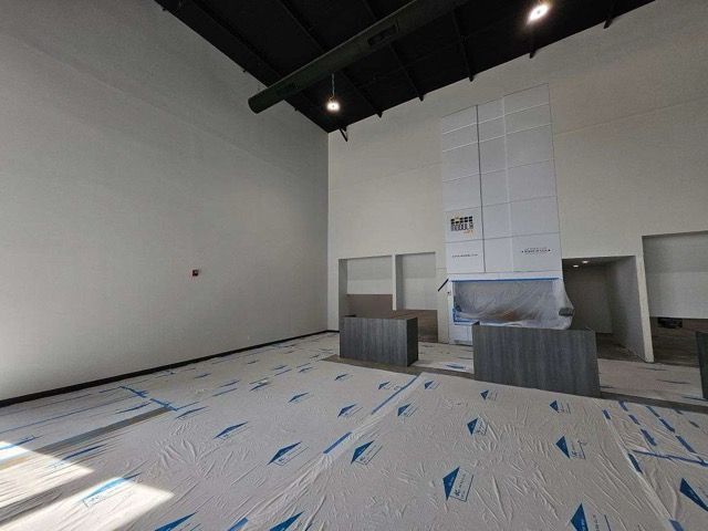 A large empty room with a fireplace in the corner.