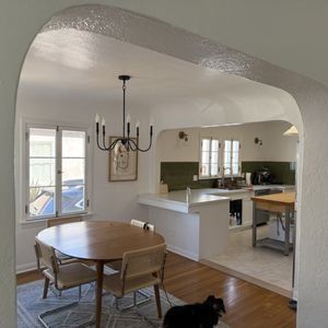 A dining room with a table and chairs and a chandelier hanging from the ceiling.