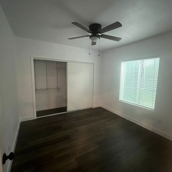 An empty bedroom with a ceiling fan and a window.