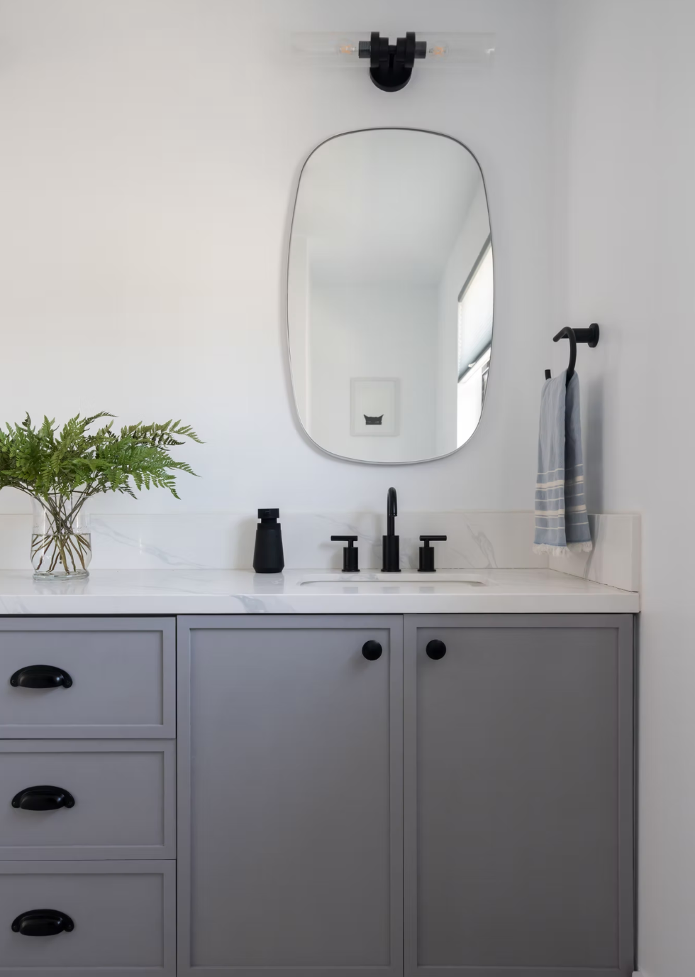 A bathroom with a tub , sink , mirror and window.