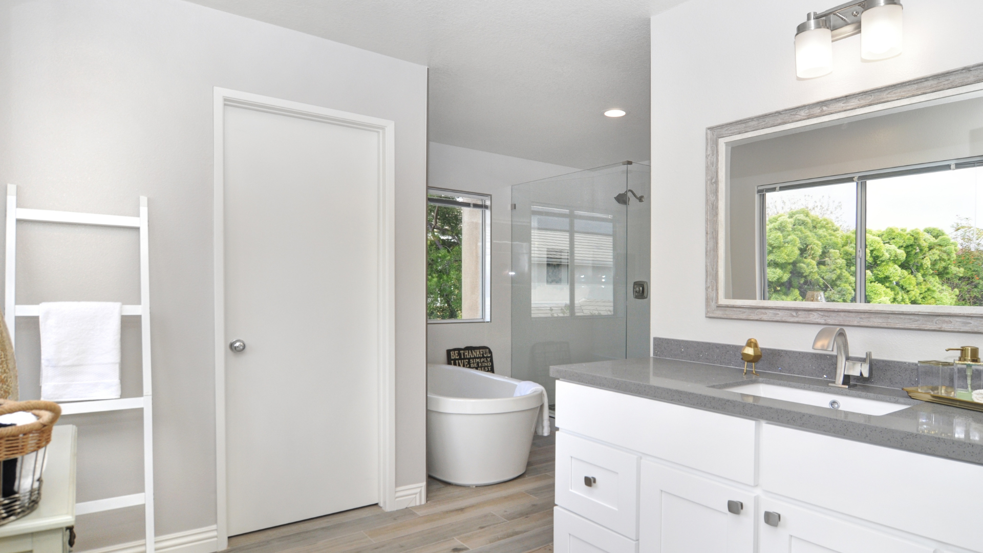 A bathroom with a tub , sink , mirror and window.